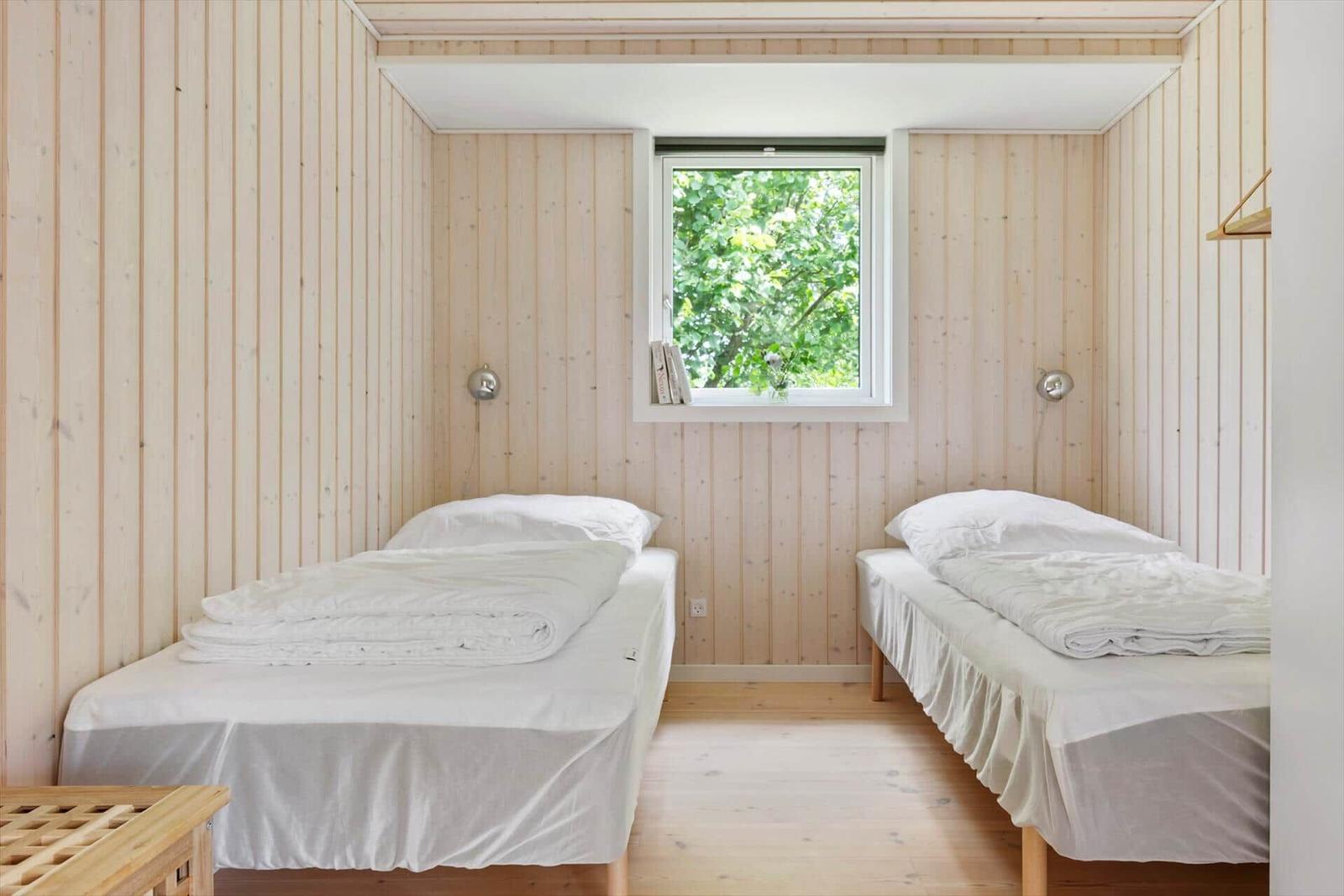 Zwei Betten in einem Raum mit Holzwandverkleidung und Fenster.