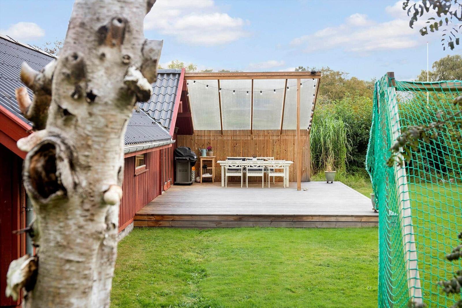 Terrasse mit Sitzgelegenheit und Grillbereich neben rotem Haus