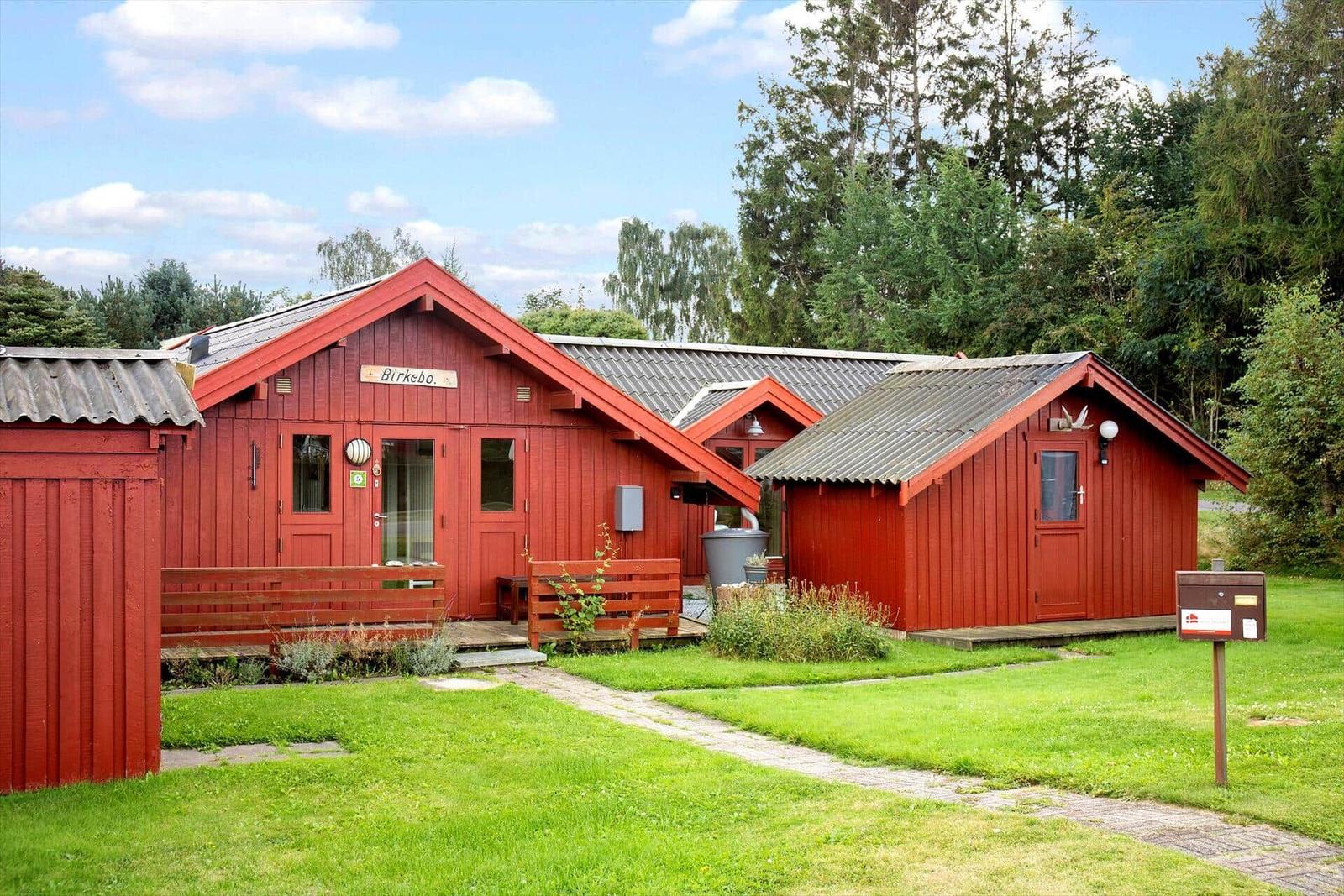 Rote Holzhütten mit Veranda und Grünfläche im Wald