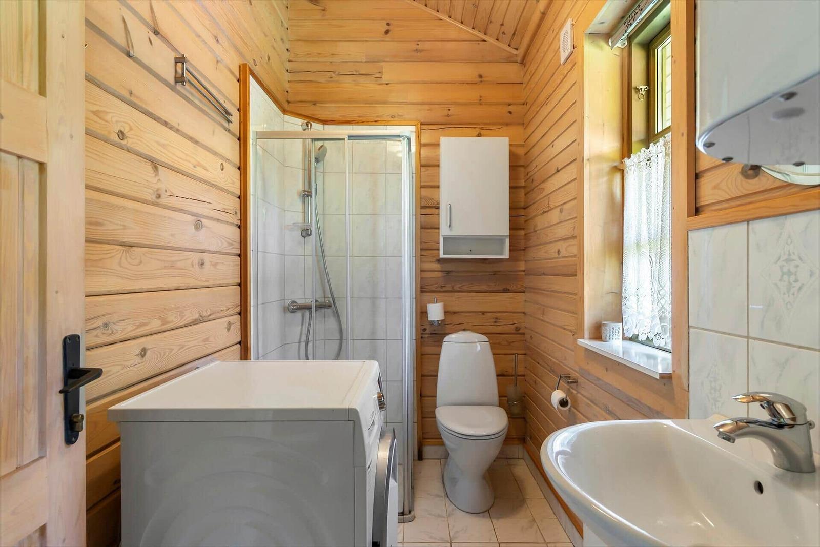 Badezimmer mit Dusche, Toilette, Waschbecken und Waschmaschine.