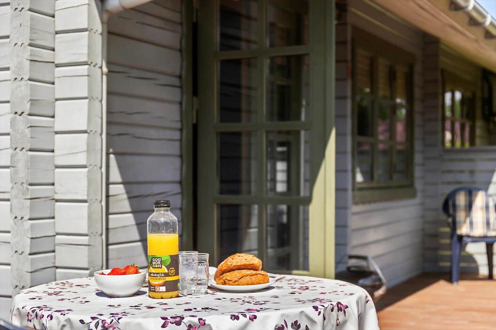 Tisch mit Frühstück auf der Terrasse vor einem Haus mit Holzfassade.