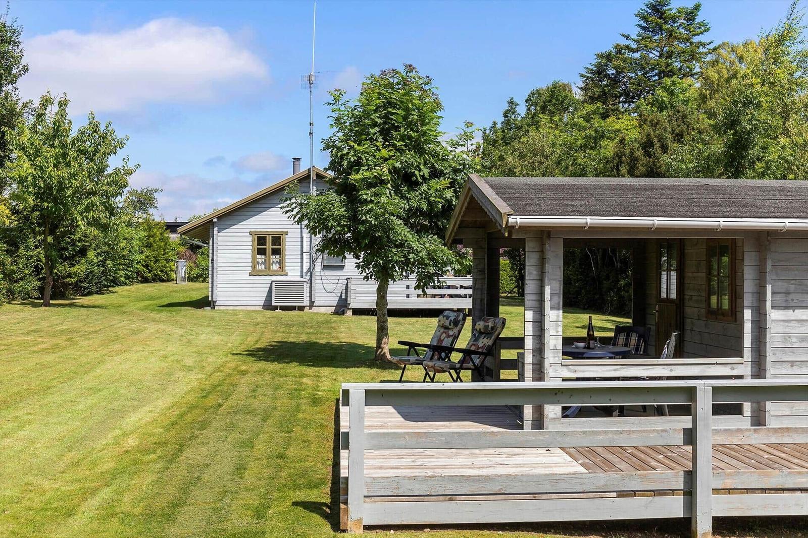 Haus mit Terrasse und Garten. Gartenmöbel und Tisch sind draußen.
