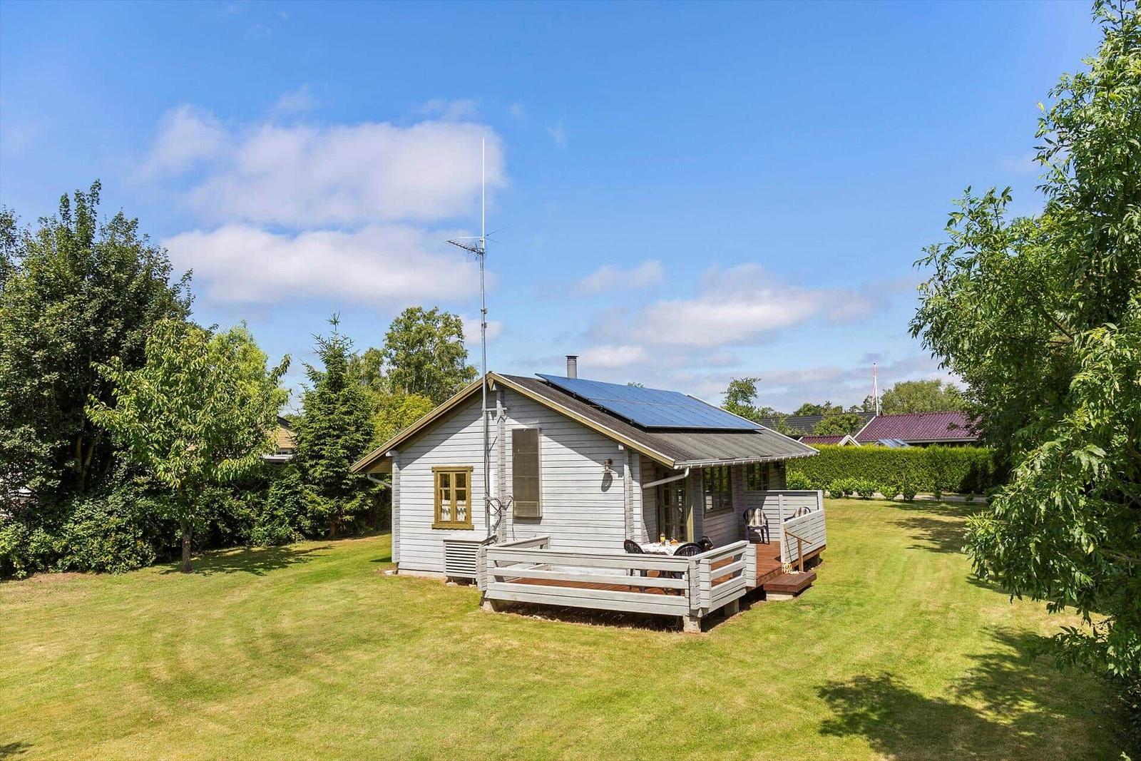 Haus mit Terrasse, Solaranlage und Garten unter blauem Himmel.
