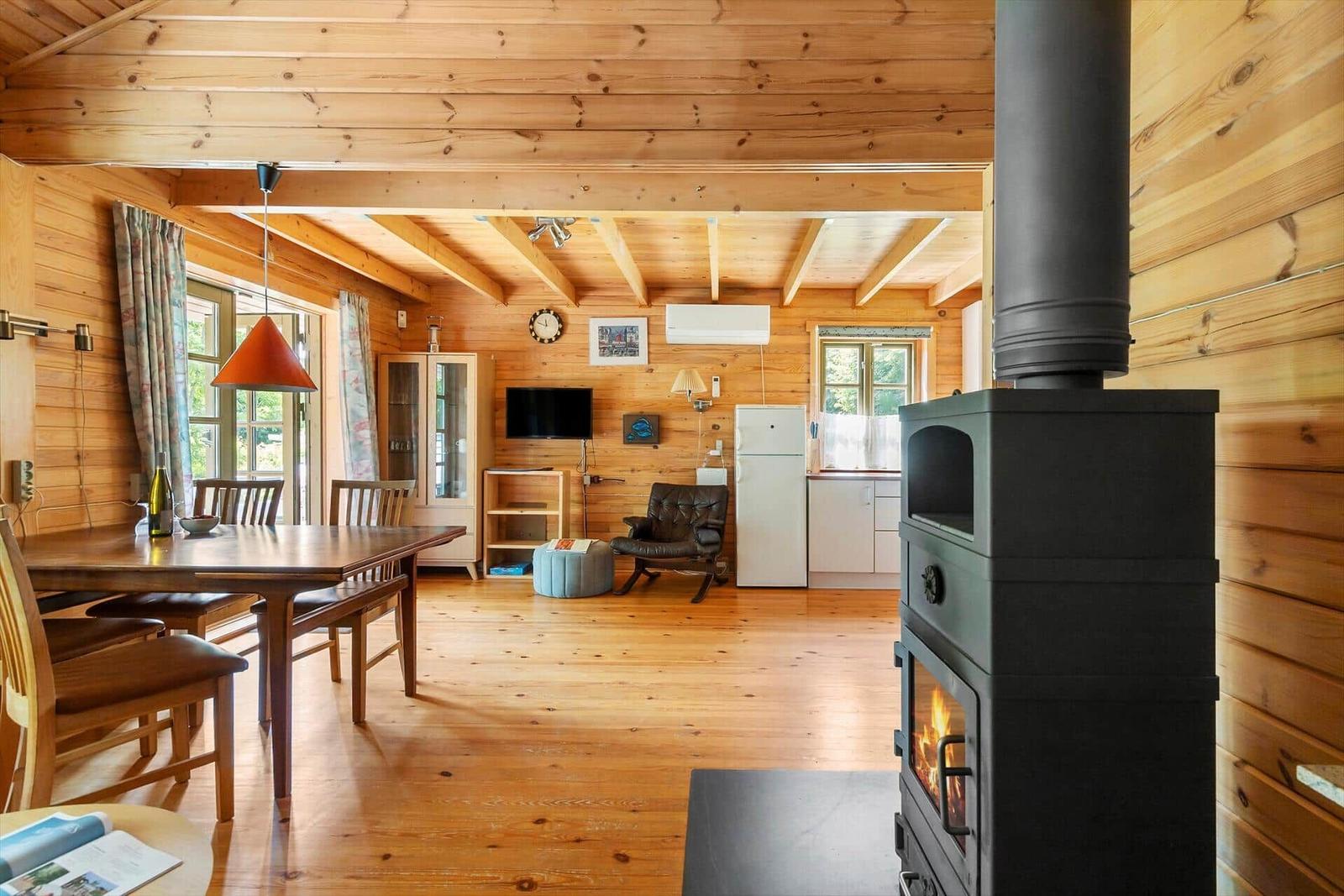 Holzhaus mit Kamin, Esstisch und Küchenbereich.