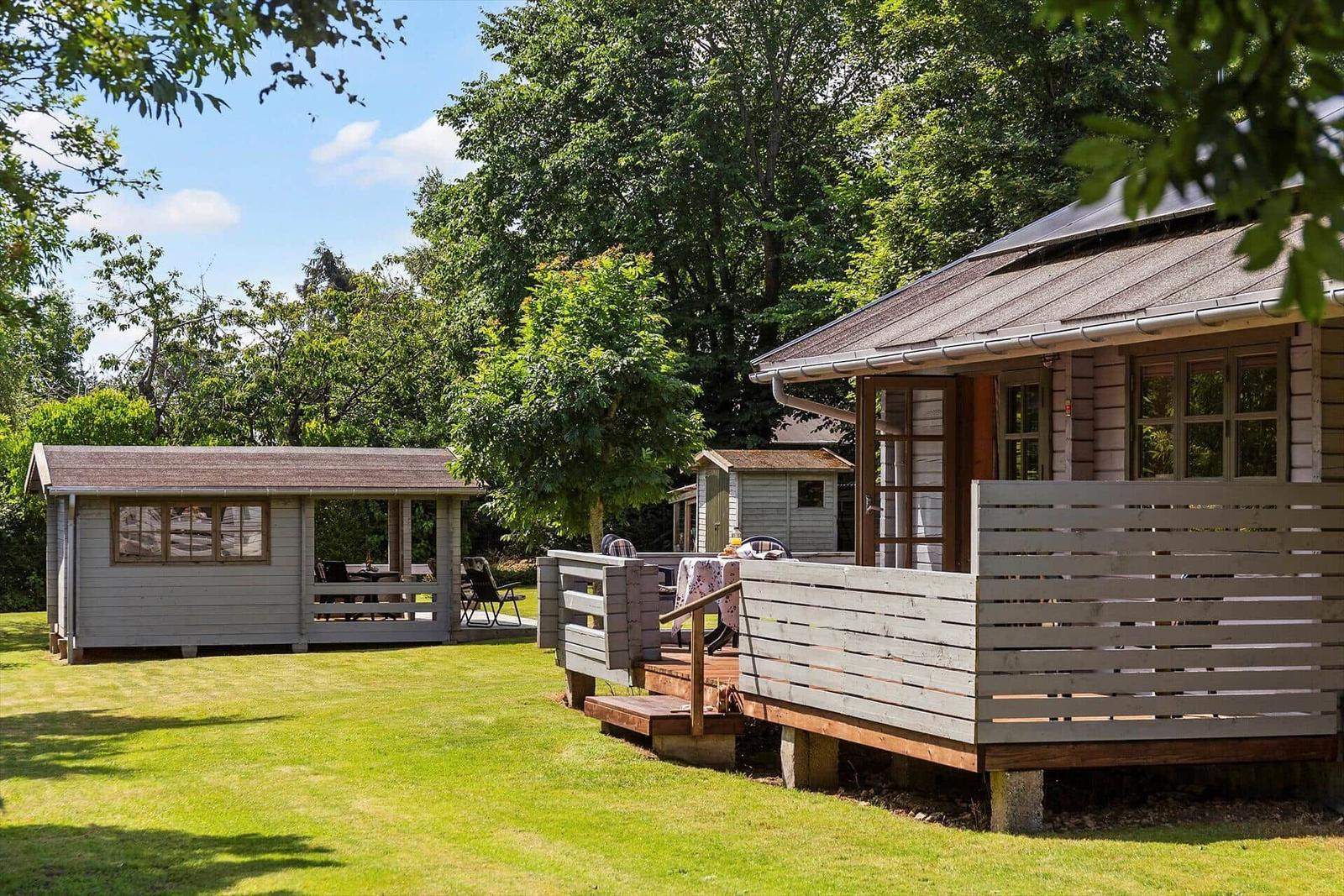 Haus mit Terrasse und Garten. Holzveranda und Grillbereich im Freien.