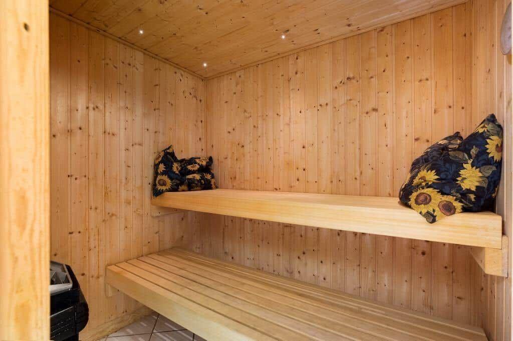 Sauna mit Holzwand, zwei Bänken und Sonnenblumenkissen.