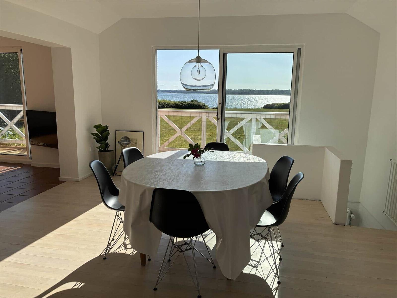 Runder Tisch mit Stühlen und Blick auf Wasser.