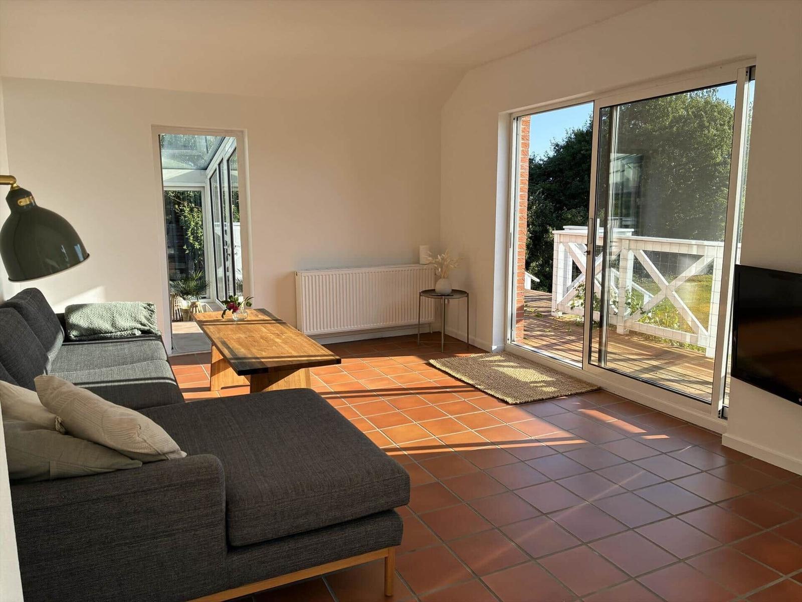 Wohnzimmer mit Sofa, Tisch und Terrassentür.