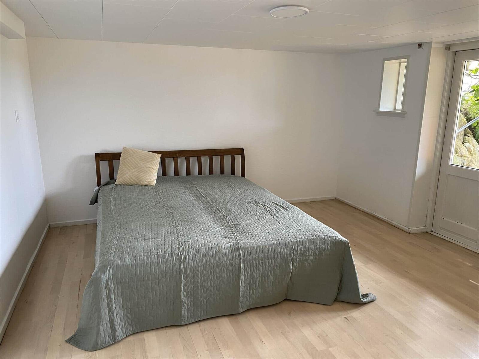 Schlafzimmer mit Bett, Holzboden und Fenster zur Außenseite.