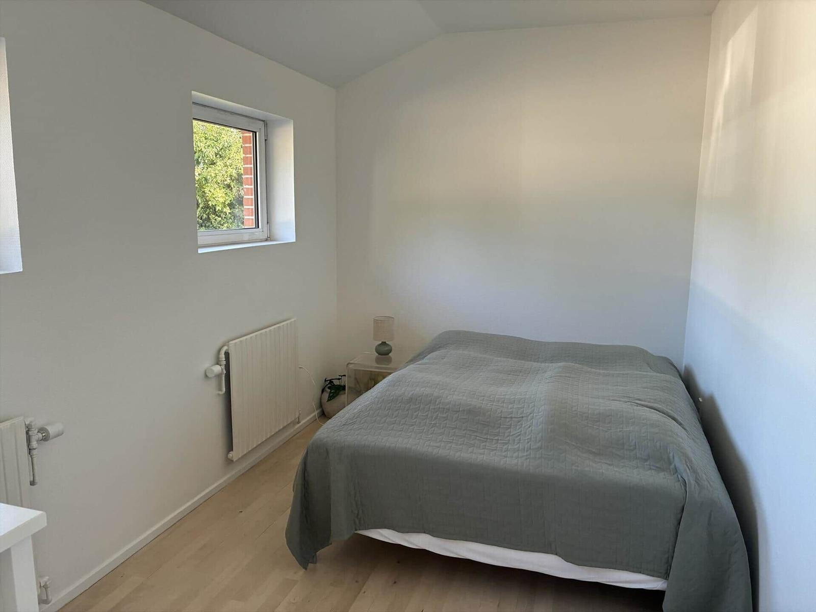 Schlafzimmer mit Bett, Fenster und Heizkörper.