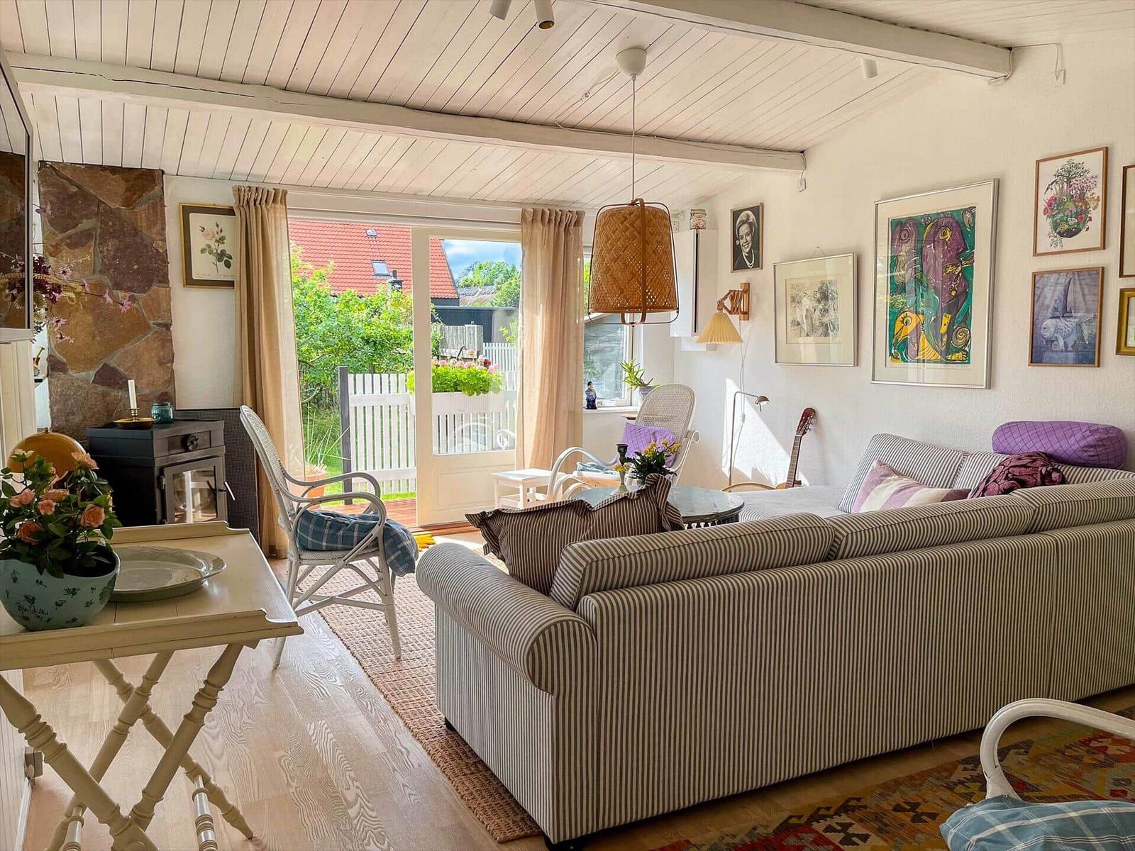 Wohnzimmer mit Sofa, Stühlen und Fenster zur Terrasse.