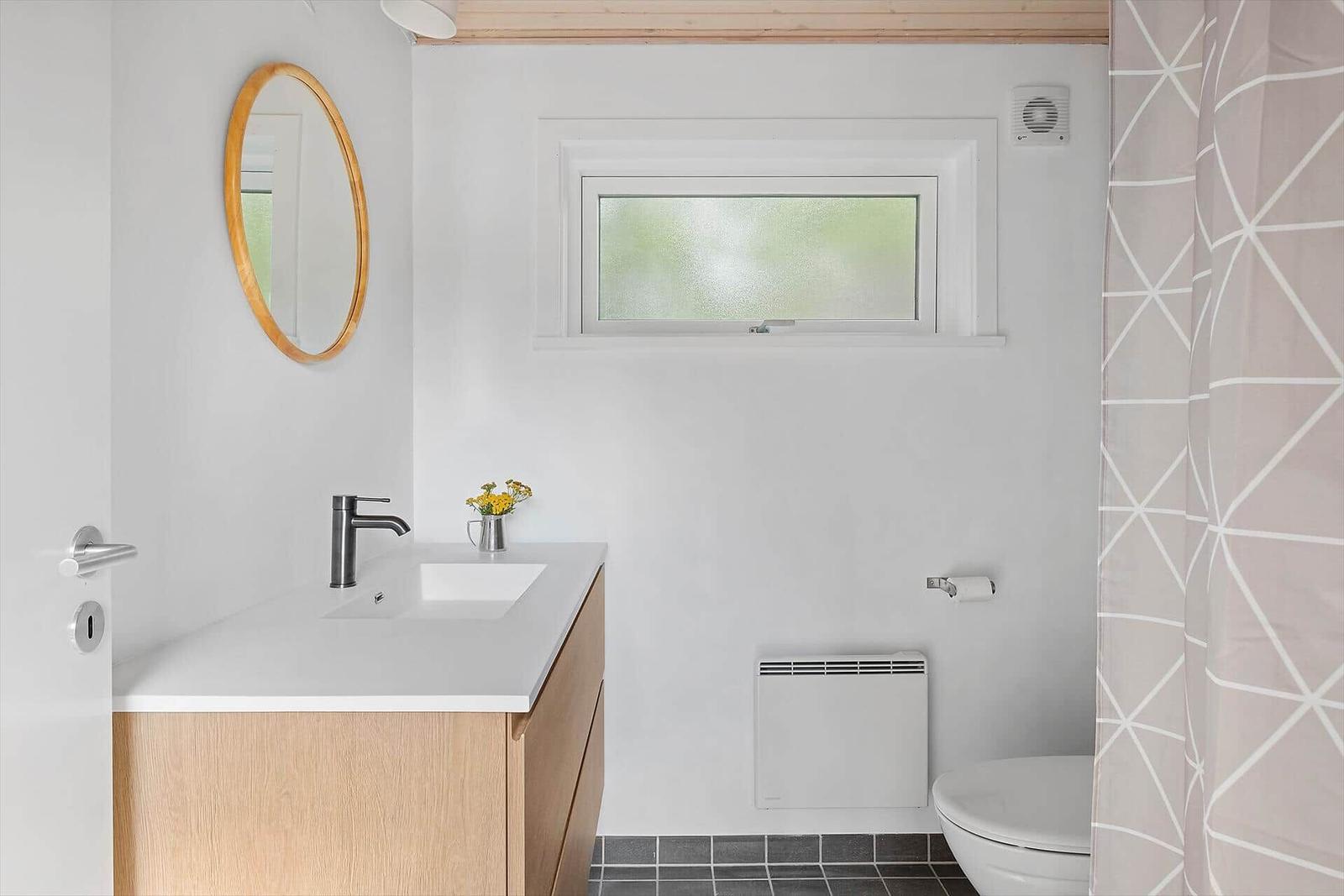 Badezimmer mit Waschbecken, Spiegel, Toilette und Dusche.