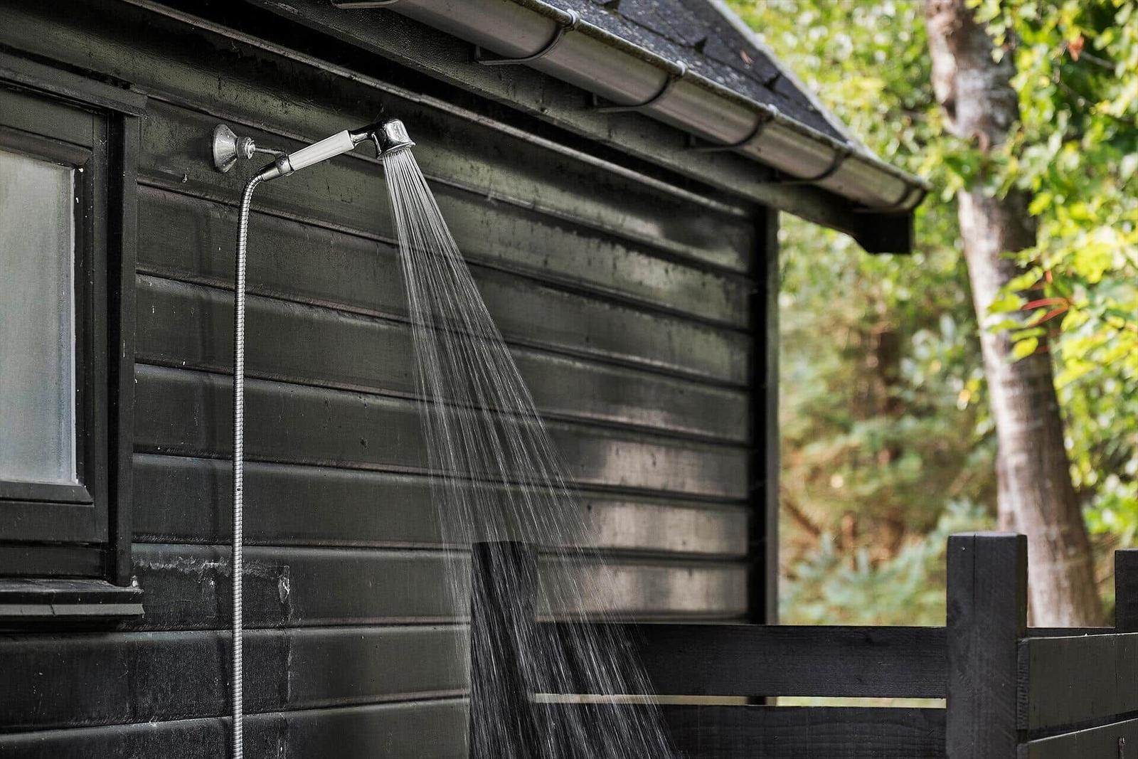 Außendusche an Holzhaus mit Wasserstrahl