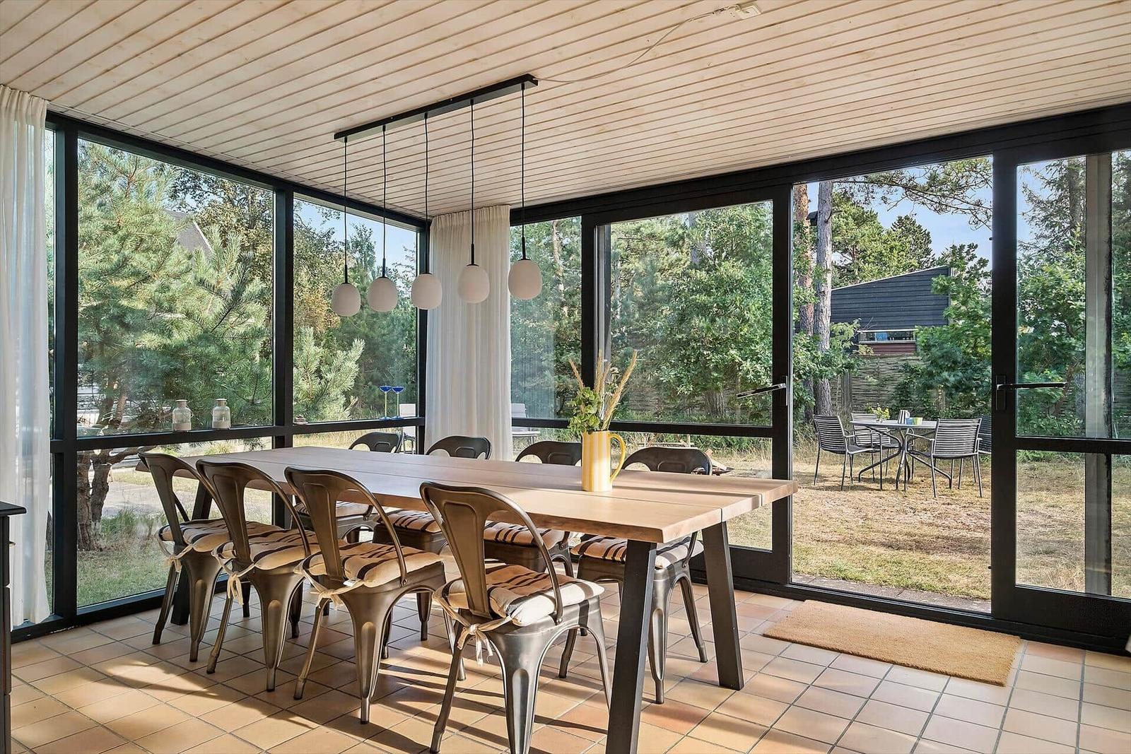 Esszimmer mit Holztisch, Metallstühlen und großem Fensterblick auf Garten.