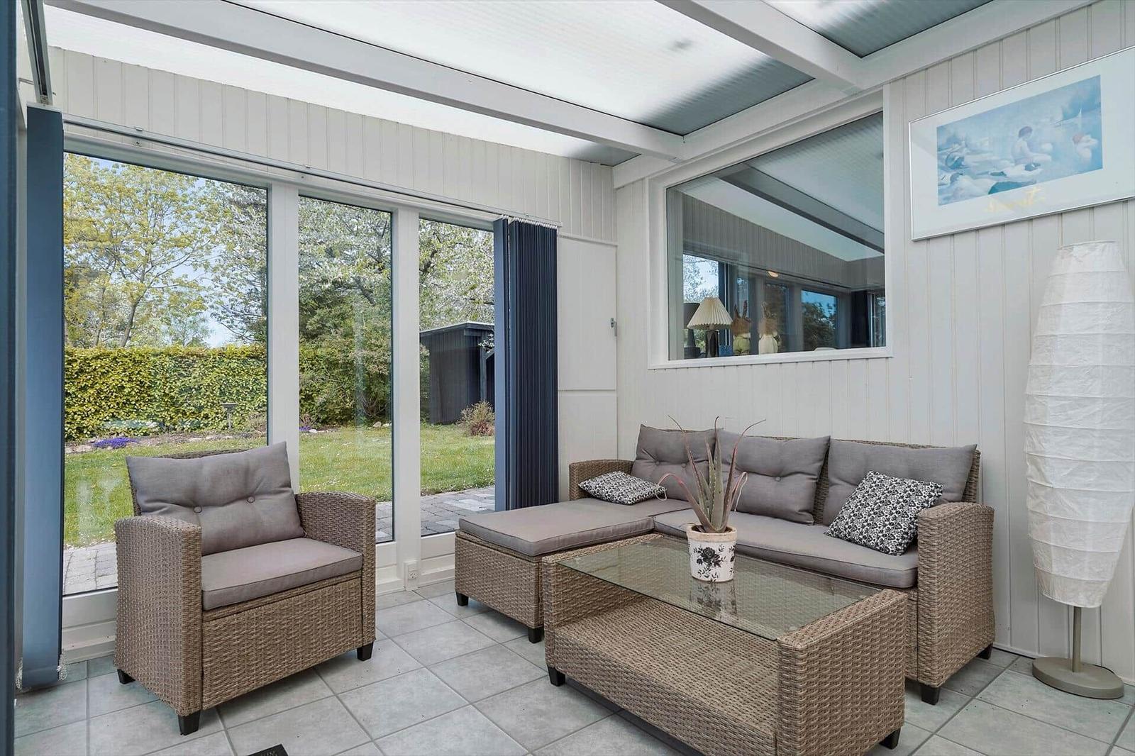 Wohnbereich mit Sitzgruppe, Glas-Tisch und Blick auf Garten.