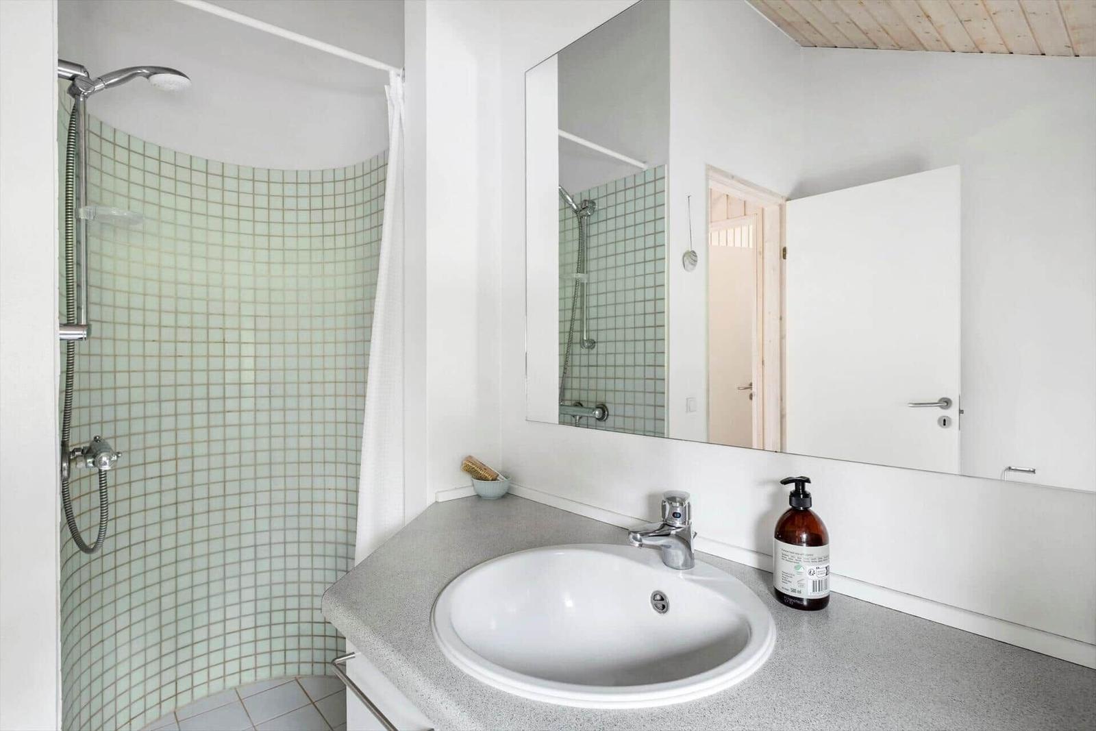 Badezimmer mit Dusche, Waschbecken und Spiegel
