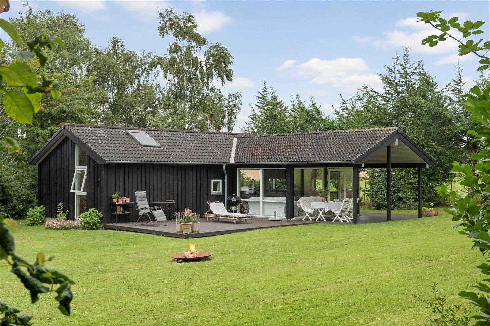Ein Haus mit Terrasse, Garten und Feuerkorb. Moderne Architektur mit Glasfront.