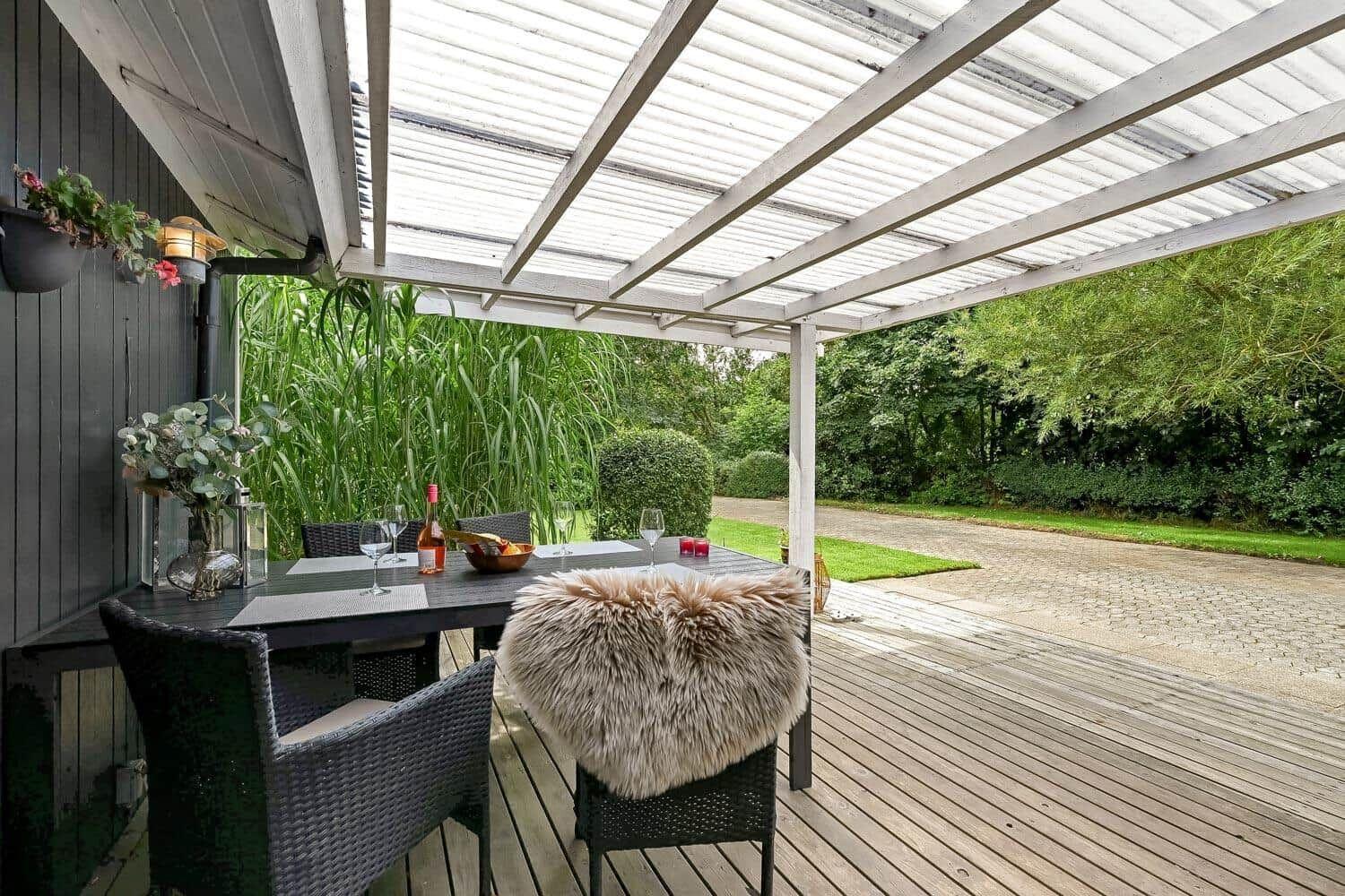 Terrasse mit Tisch, Stühlen und Felldecke unter Dach