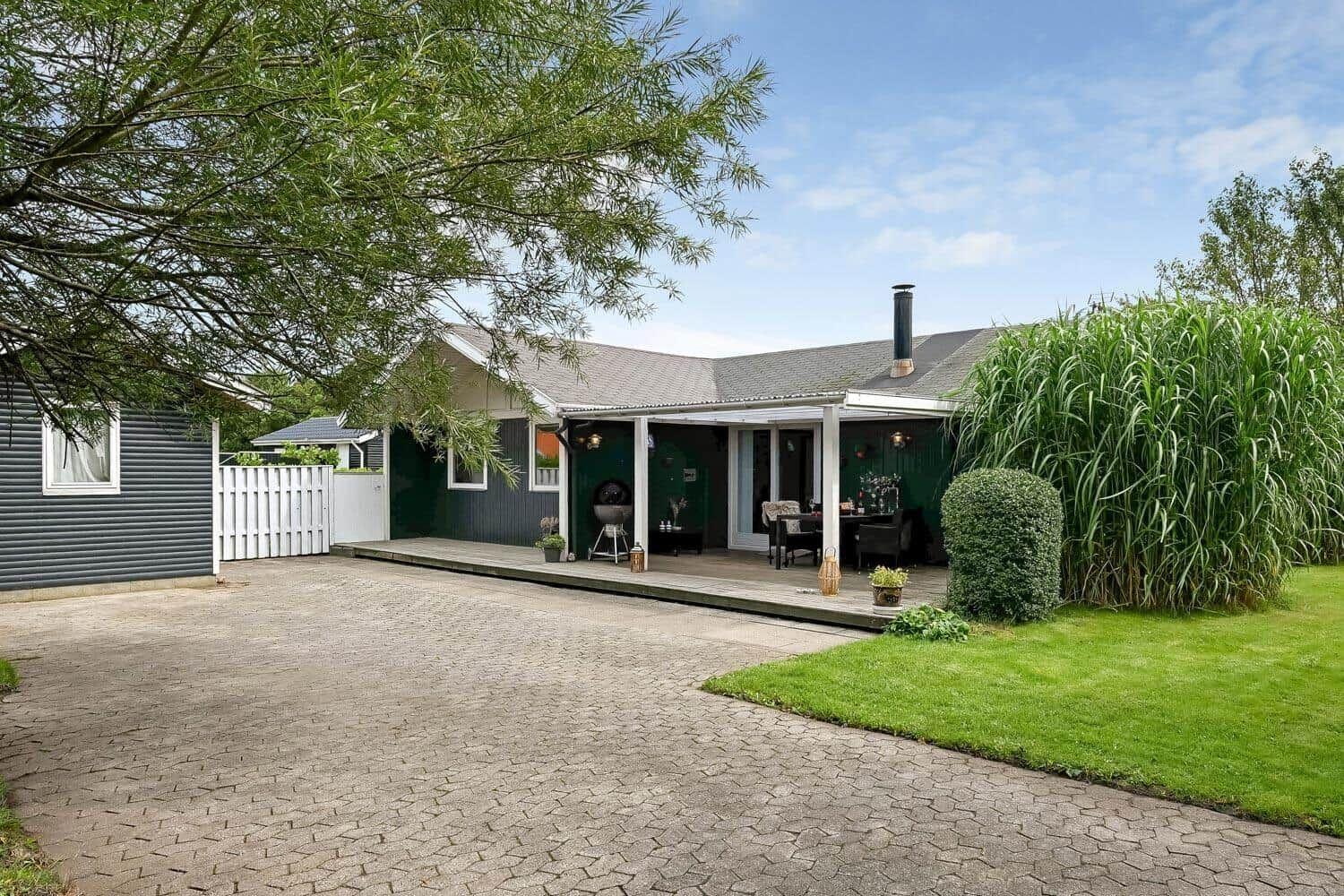 Haus mit Terrasse, Grill und Garten. Weiße Veranda mit Tisch und Stühlen.