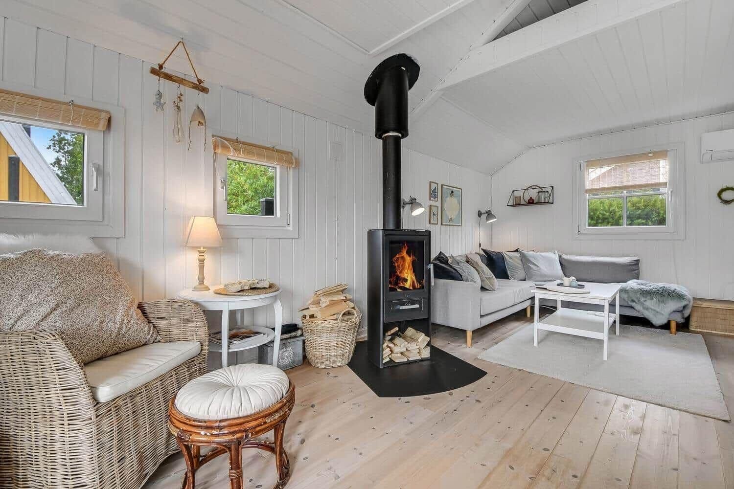 Wohnzimmer mit Kamin, Sofa und Sitzgelegenheiten. Holzboden und weiße Wände.