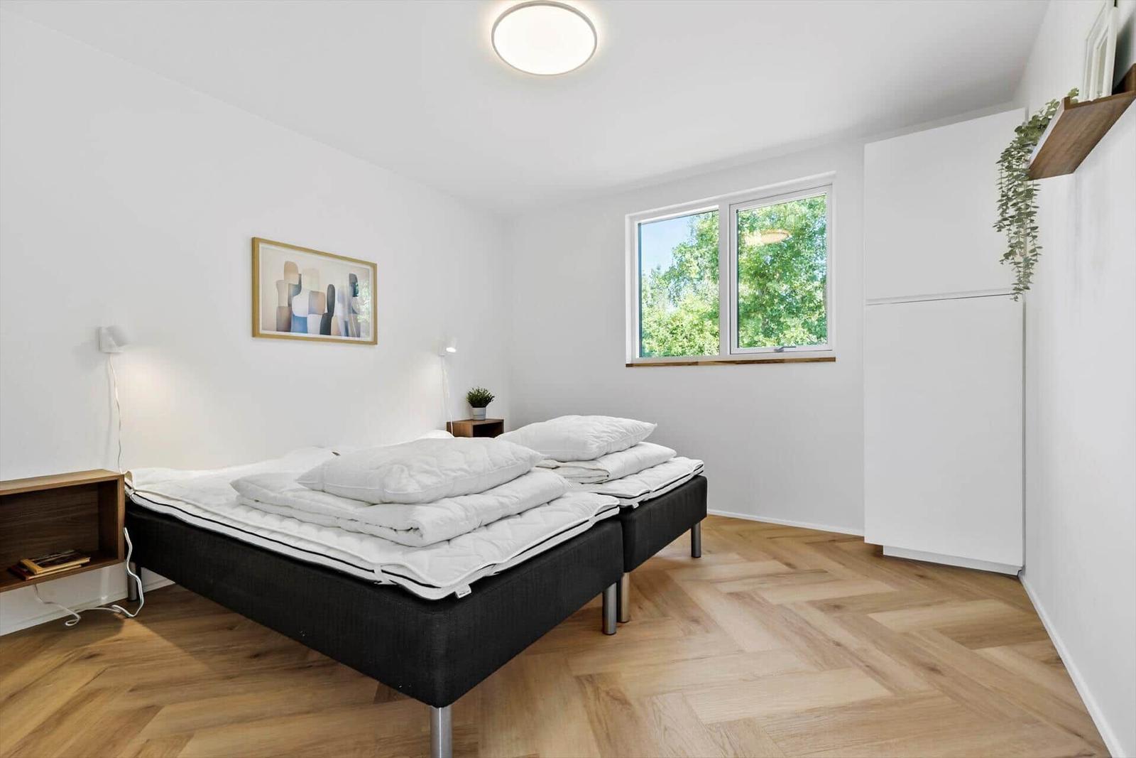 Schlafzimmer mit Doppelbett, Fenster und Holzboden.