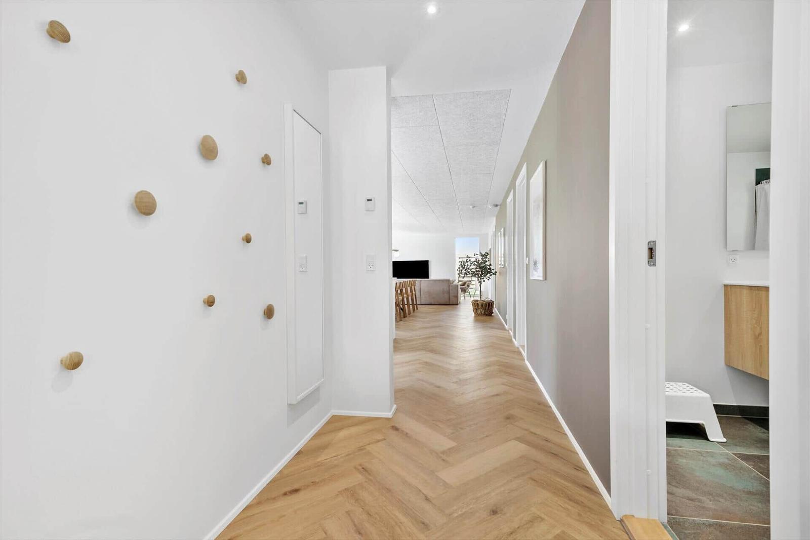 Flur mit Holzboden und Wanddekoration. Blick in Wohn- und Badezimmer.