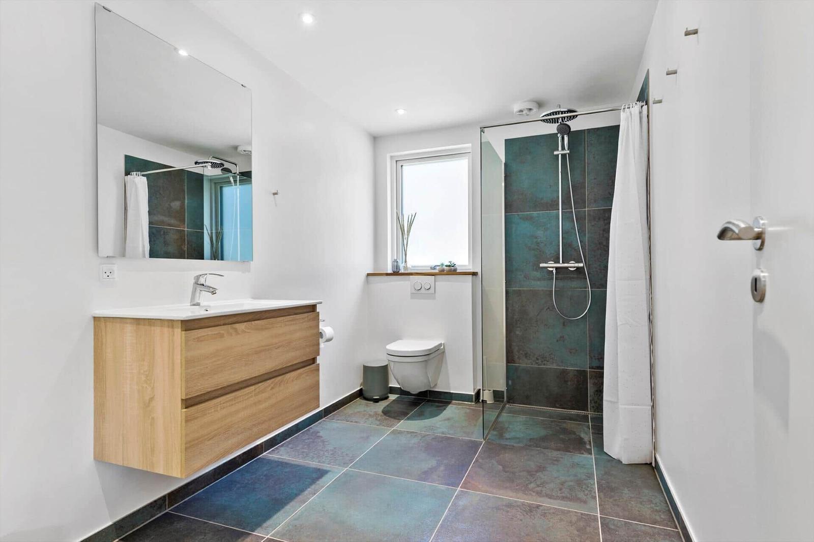 Badezimmer mit Dusche, Waschbecken und Toilette.