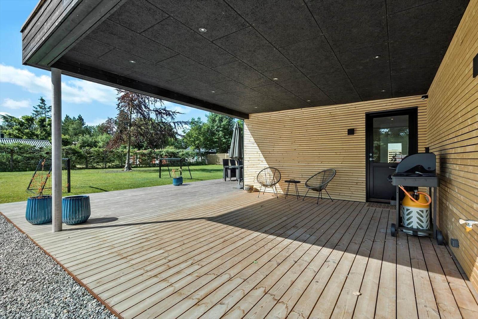 Terrasse mit Grill, Stühlen und Blick auf den Garten.