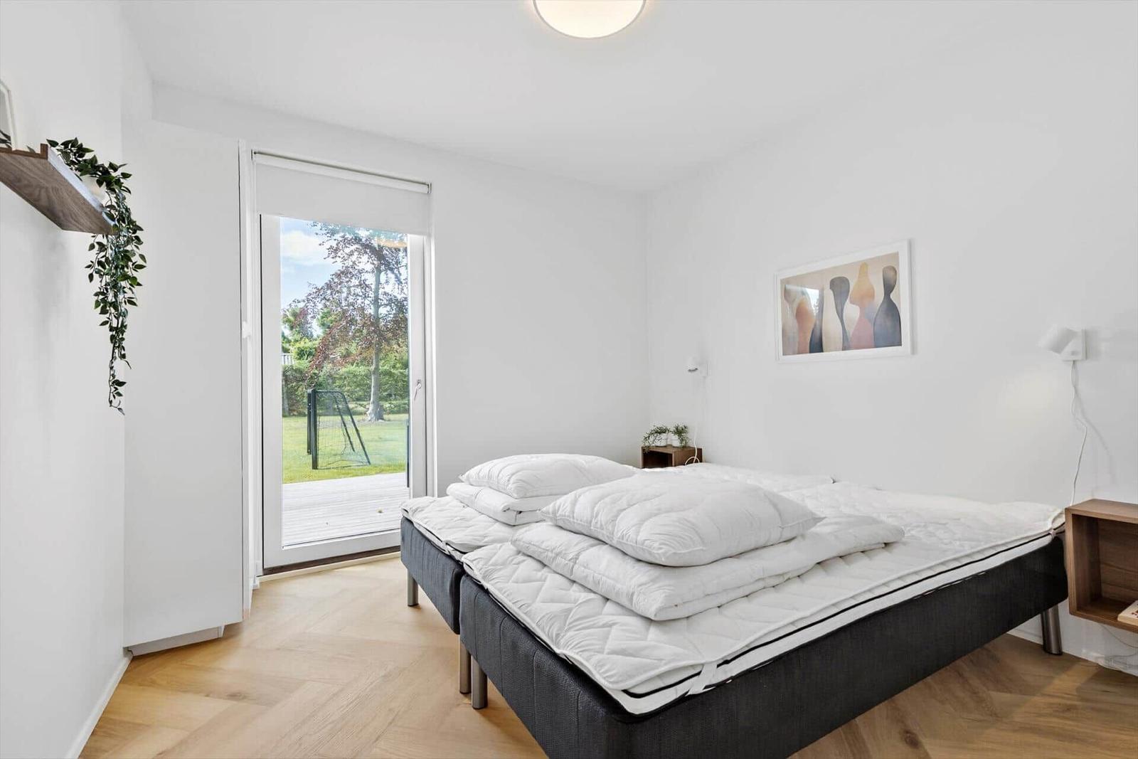 Schlafzimmer mit Bett, Tür zum Garten und Wandbild.