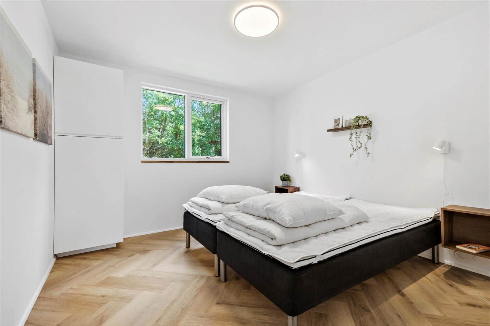 Schlafzimmer mit Bett, Fenster und Holzboden.