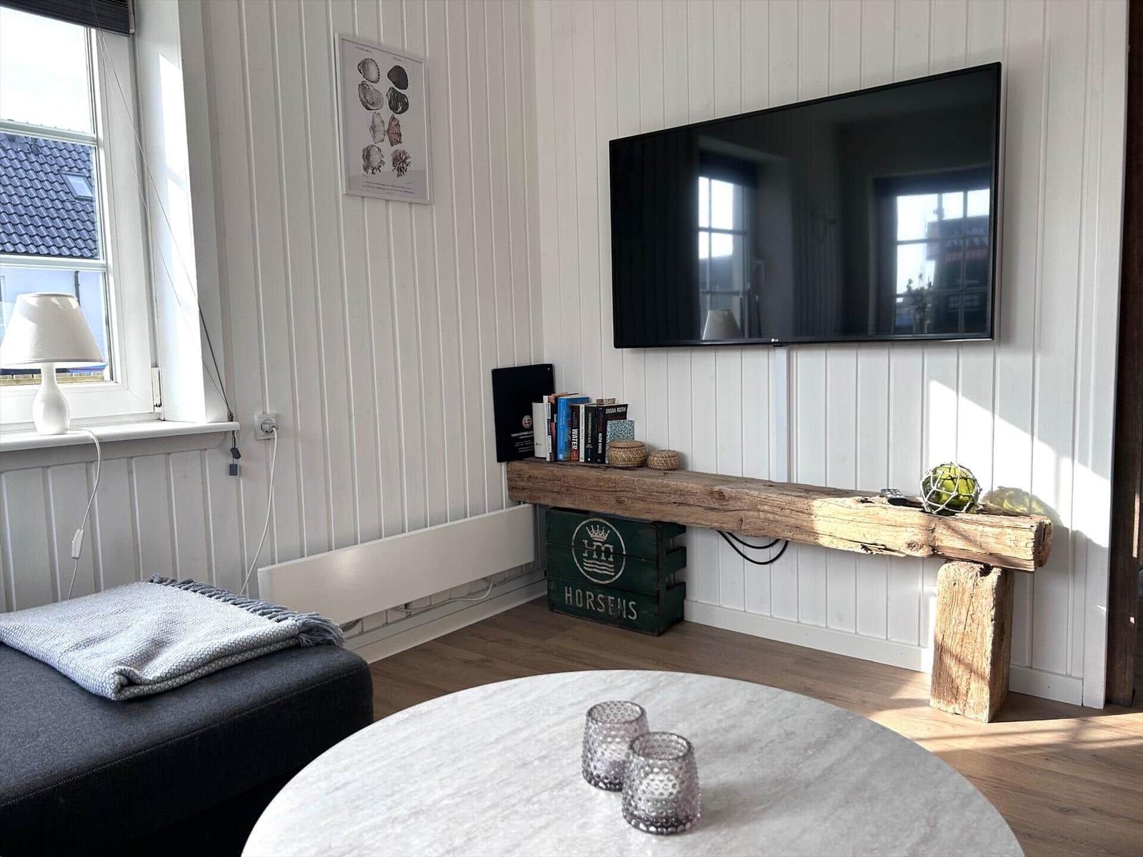 Wohnzimmer mit Fernseher, Holzbank und runder Tisch