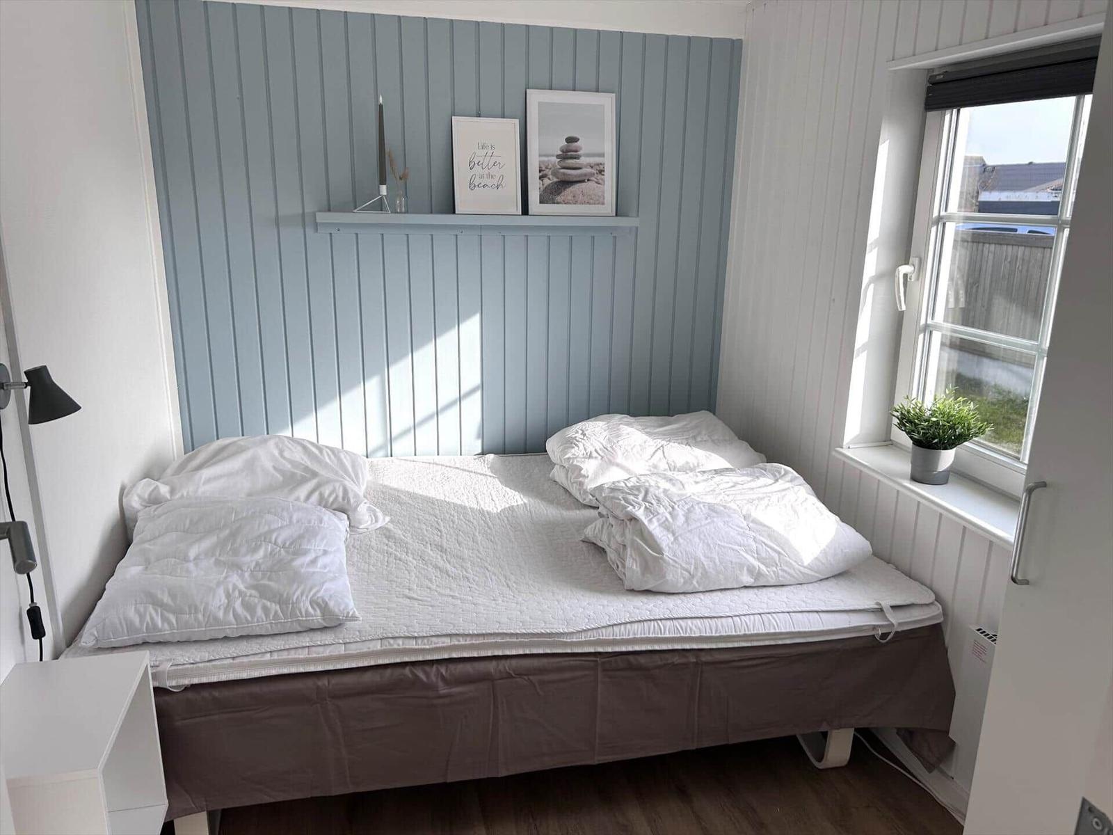 Schlafzimmer mit Bett, Fenster und Wanddekoration.