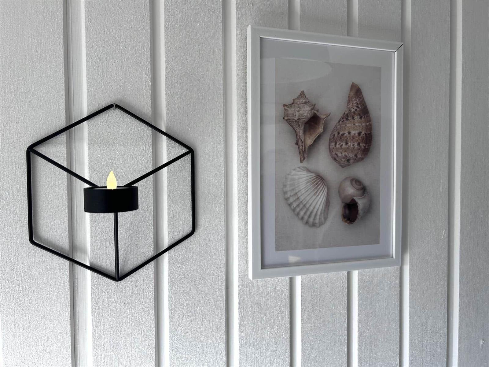Wand mit schwarzem Hexagon-Lampe und gerahmten Muscheln