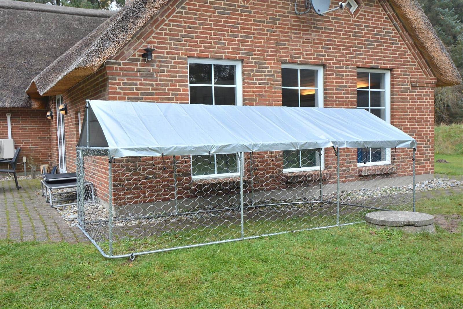 Hütte mit Metallzelt und Drahtzaun im Garten