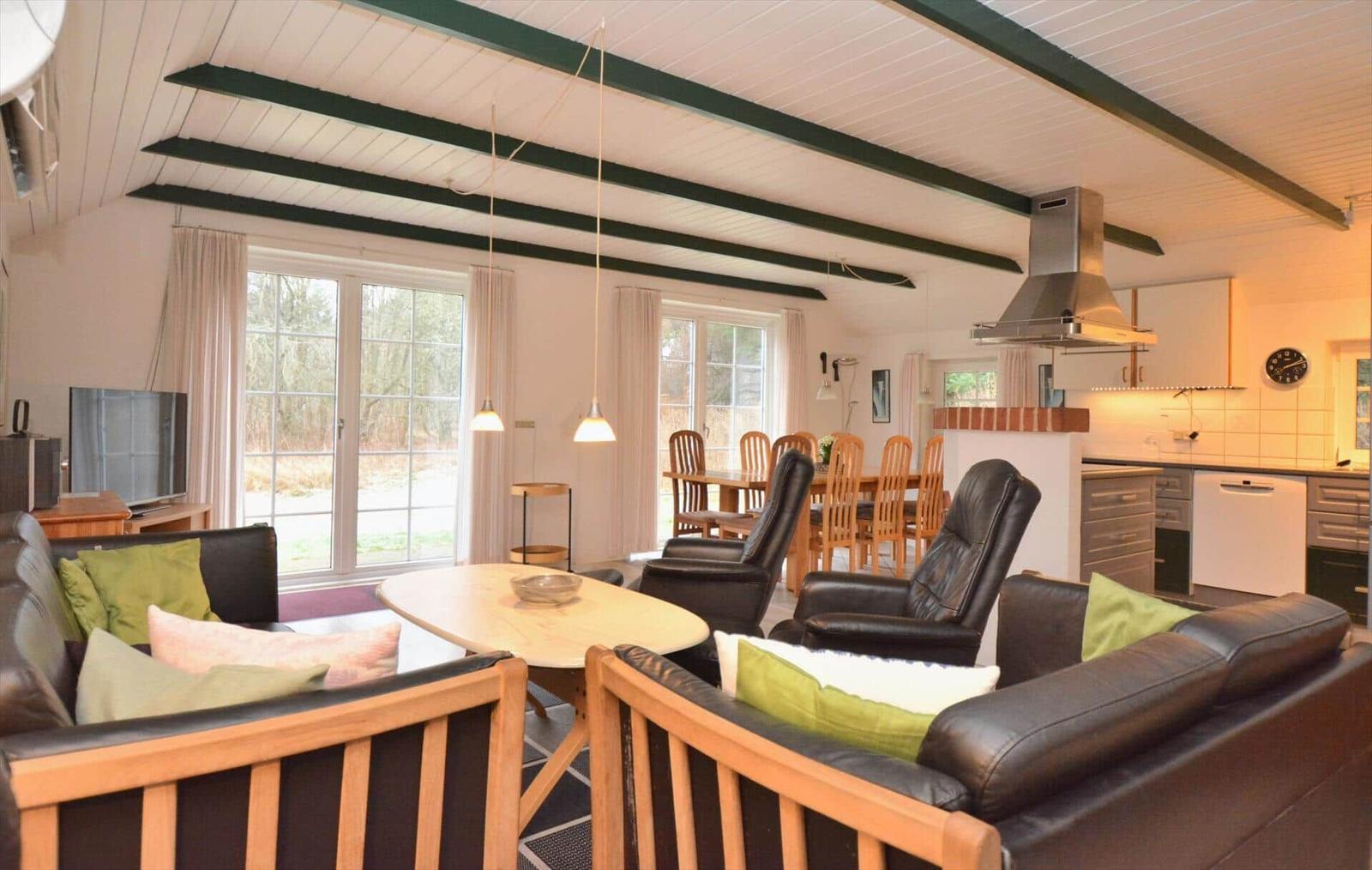 Wohn- und Essbereich mit Küchenzeile und großen Fenstern.