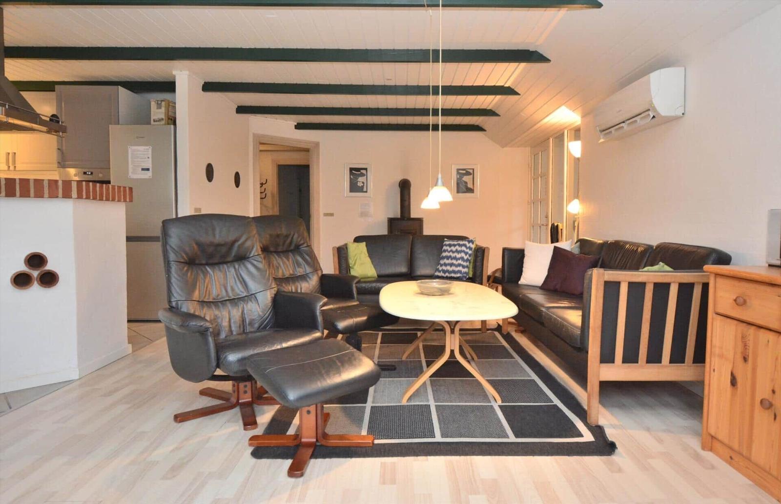 Wohnbereich mit Ledersofa, Sessel und Esstisch auf Teppich