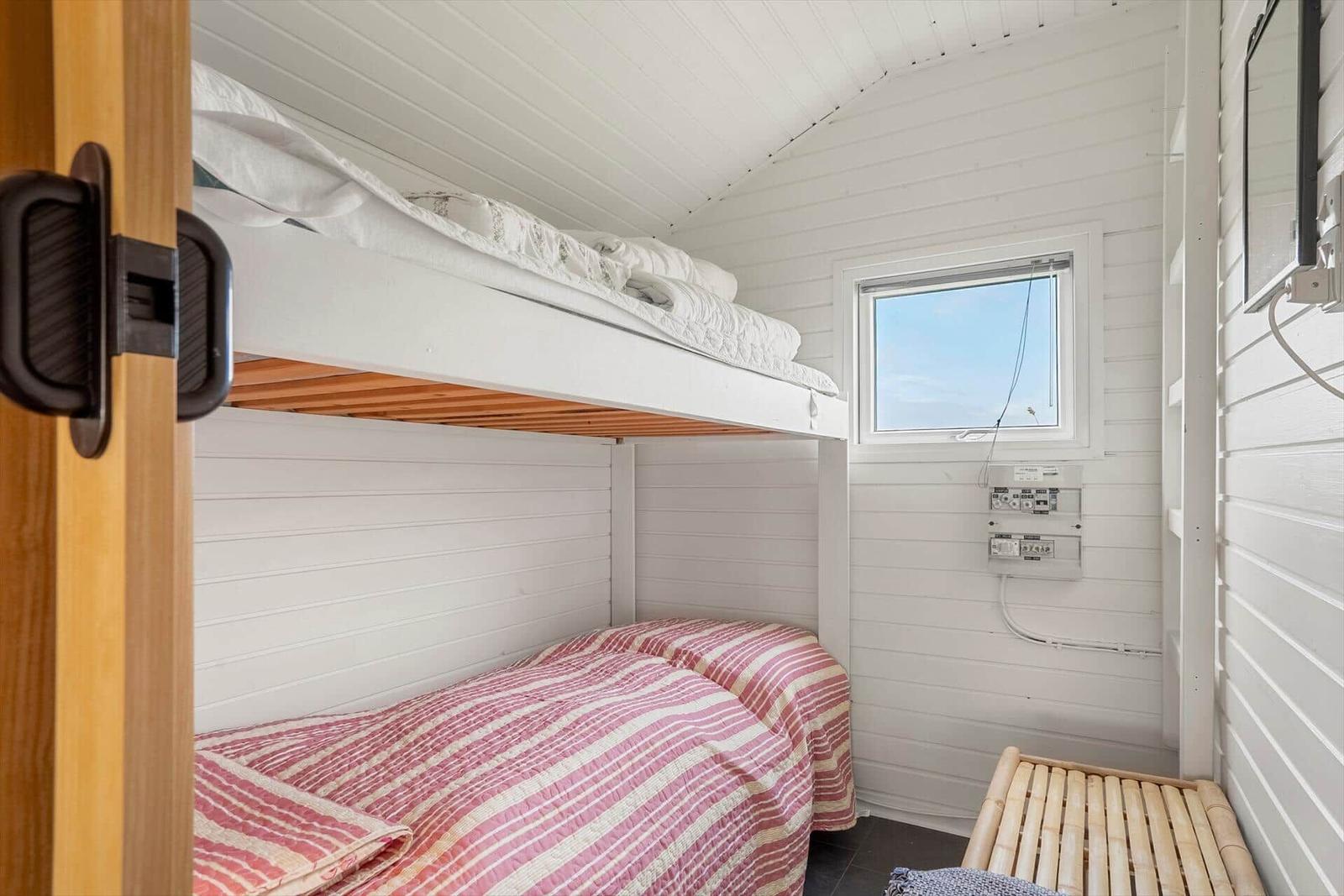 Zimmer mit Doppelstockbett, Fenster und Bambusbank.