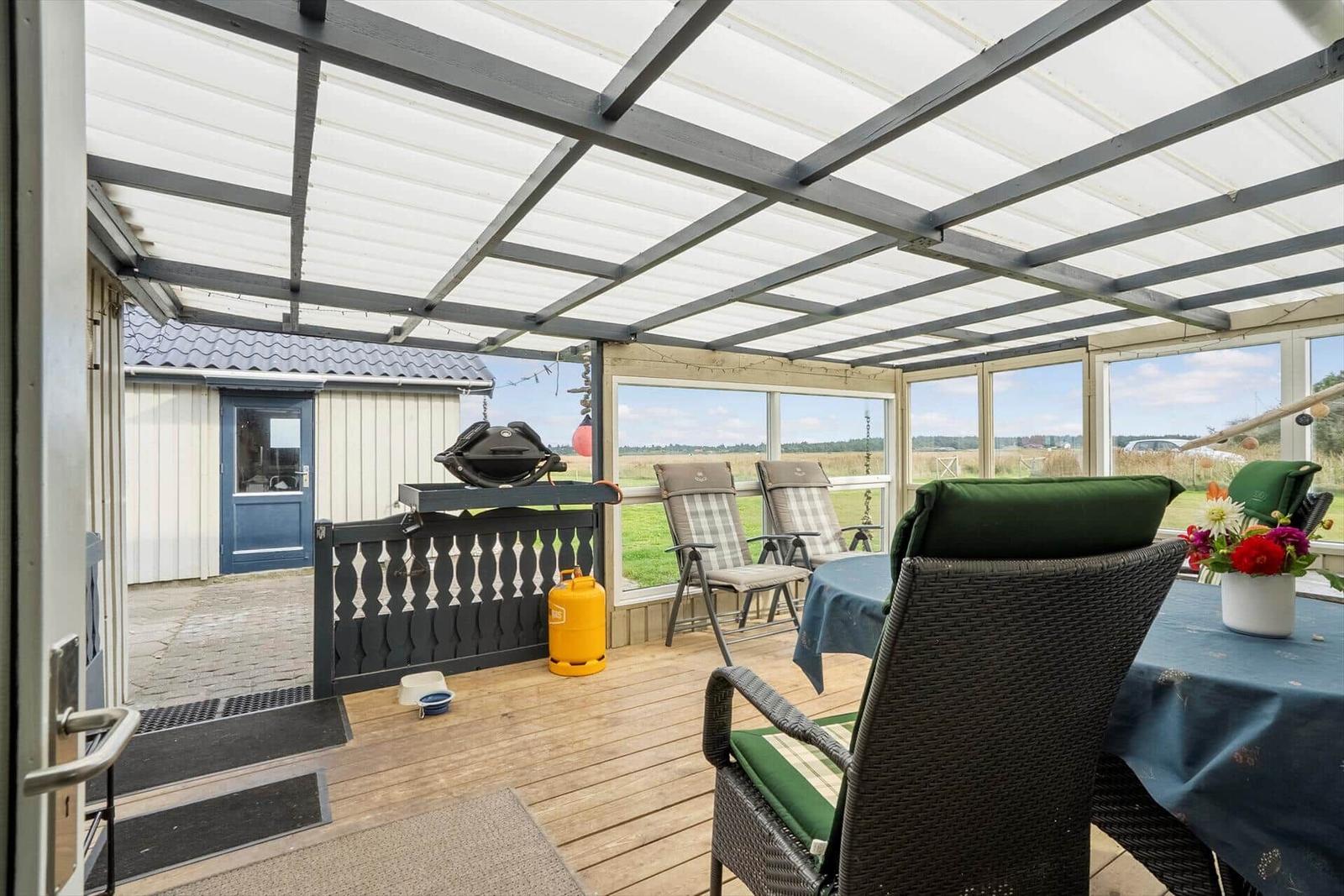 Terrasse mit Sitzgruppe, Grill und Tisch unter Dach