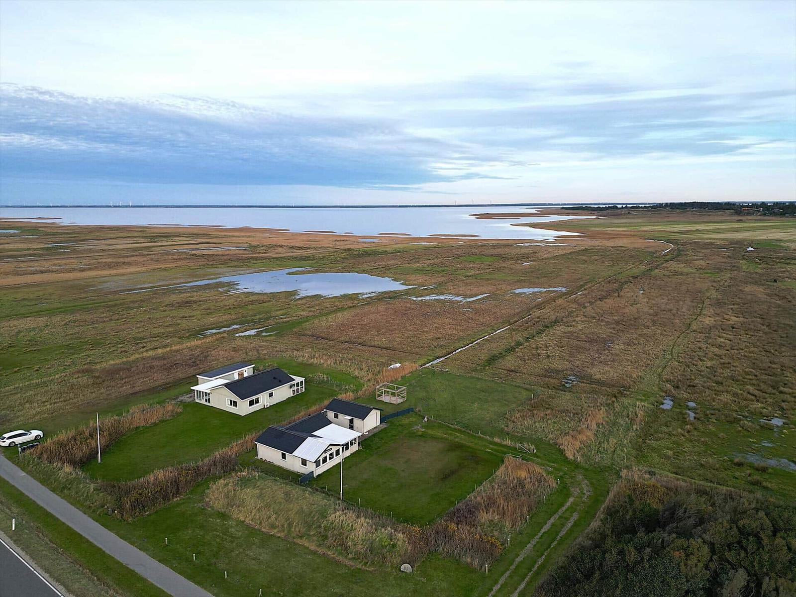 Zwei Häuser auf einer grünen Wiese am Wasser mit Blick auf die Landschaft.