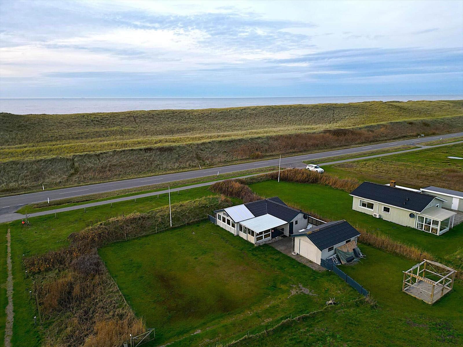 Haus mit Garten, Straße und Meer im Hintergrund.