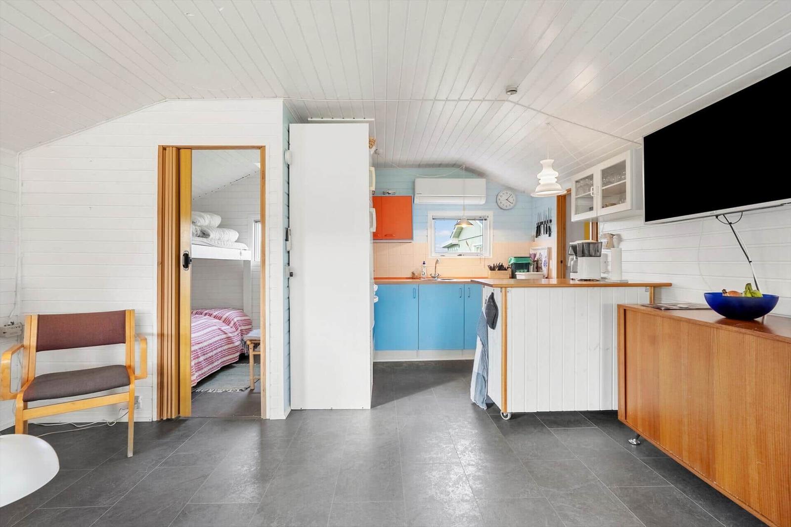 Küche mit blauen Schränken und Schlafbereich mit Hochbett.