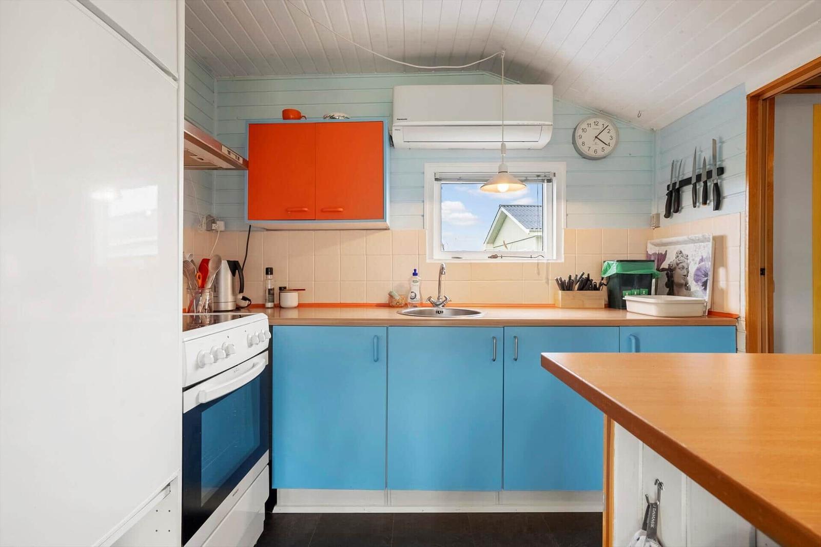Küche mit blauen Schränken, orangefarbenem Oberteil und Kücheninsel.