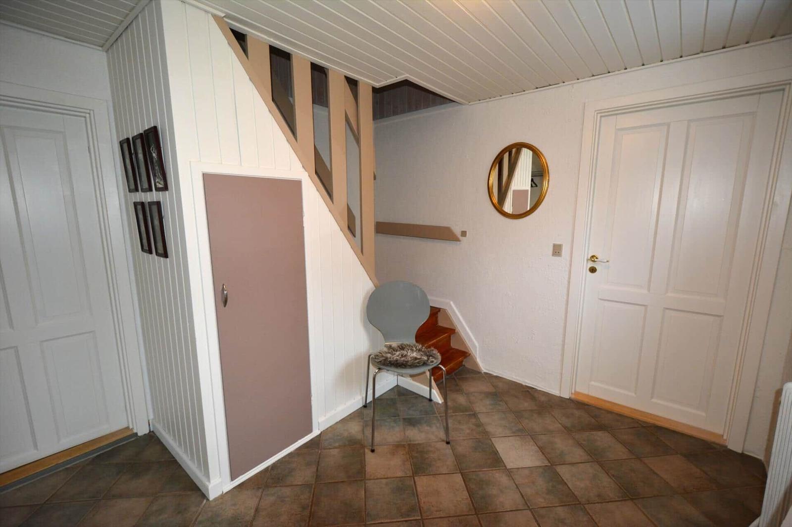 Eingangsbereich mit Stufen, Stuhl und Spiegel an der Wand.