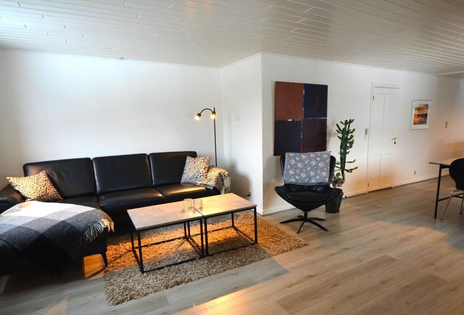 Wohnzimmer mit Sofa, Sessel, Couchtisch und Wandbild.