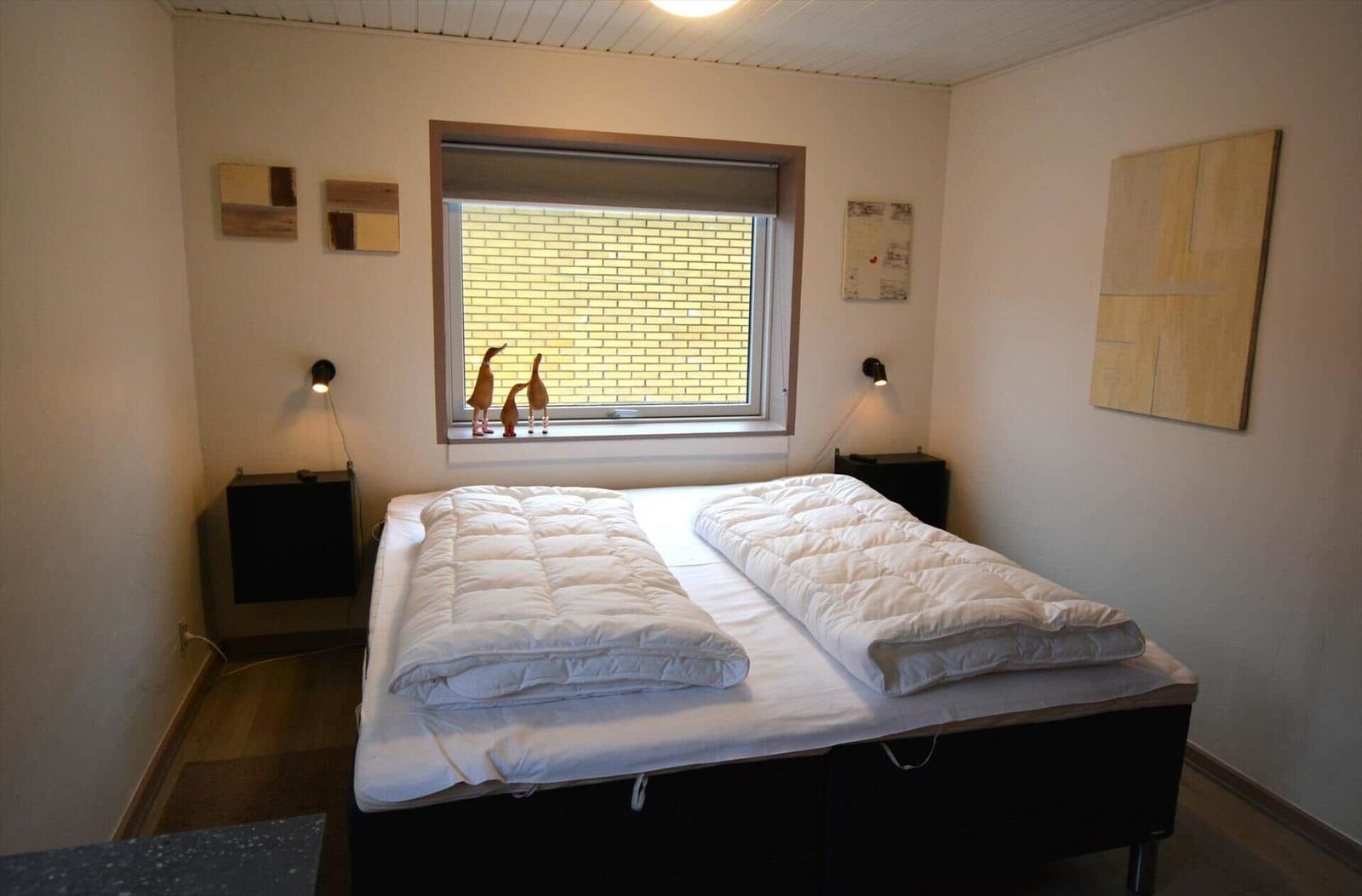 Schlafzimmer mit Doppelbett, Fenster und Wanddekoration.