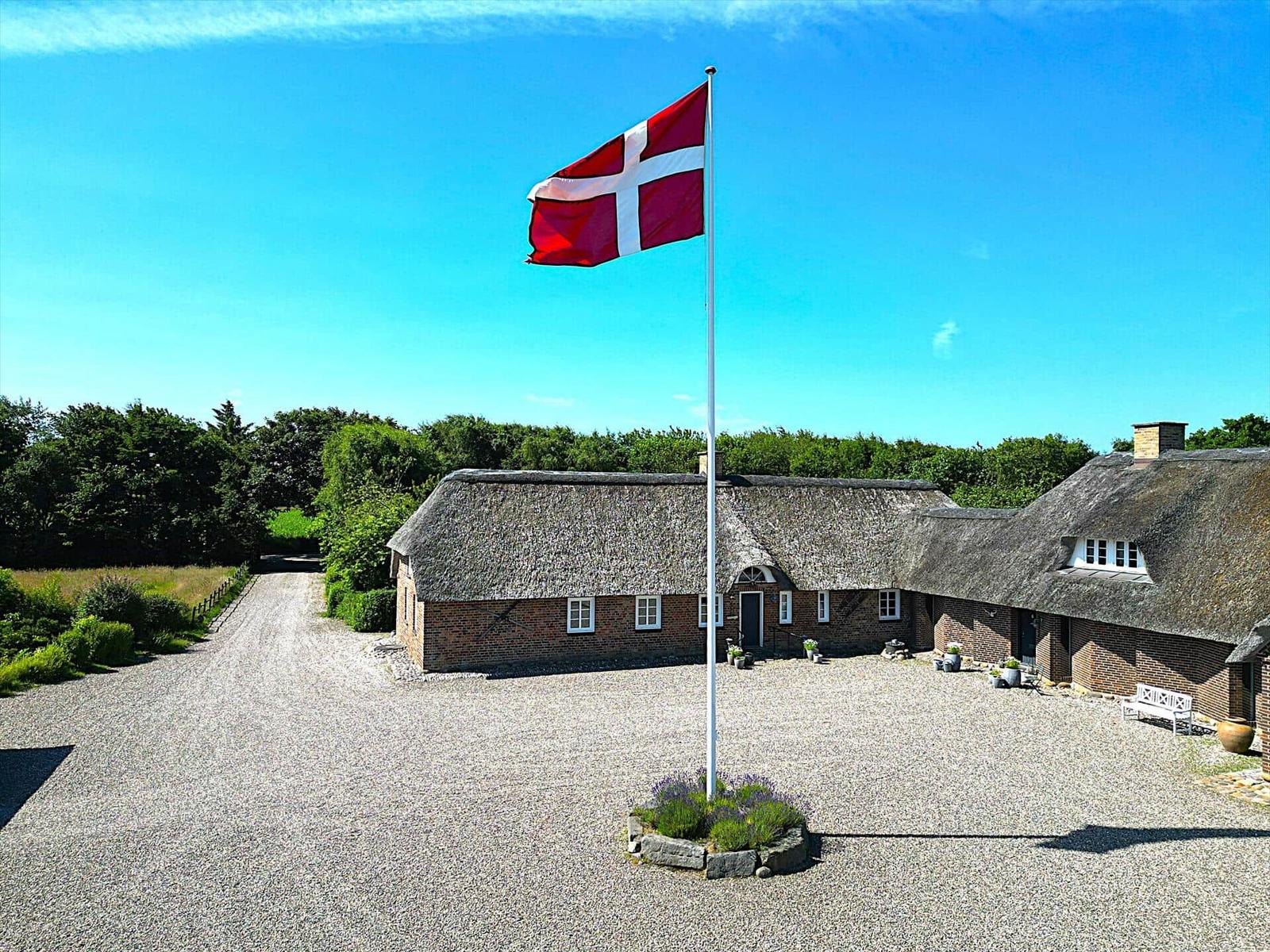 Traditionelles Dänemarkhaus mit Strohdach und dänischer Flagge auf dem Hof.