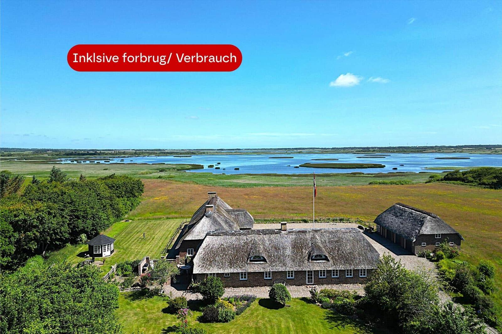 Haus mit Strohdach und Garten neben Wasserfläche