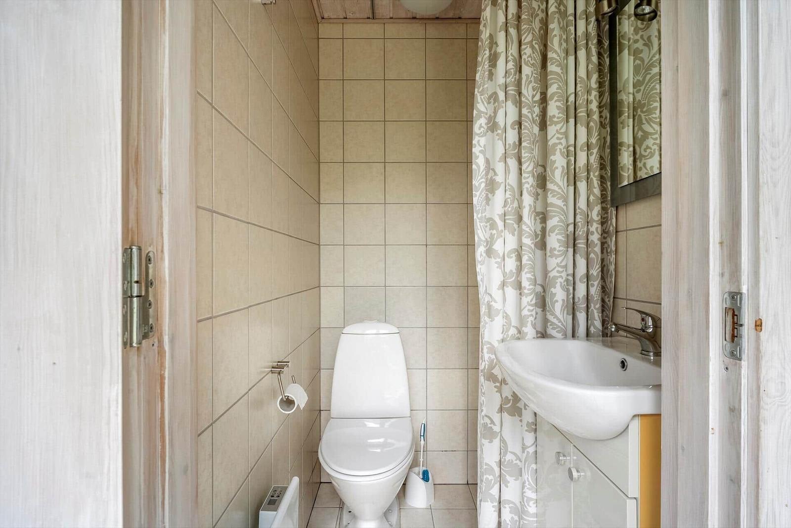 Badezimmer mit Toilette, Waschbecken und Duschvorhang.