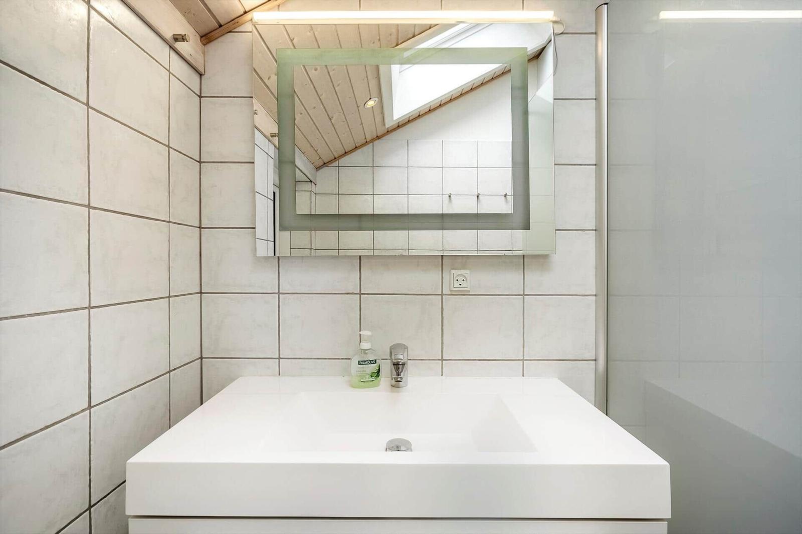 Badezimmer mit Waschtisch, Spiegel und Dusche