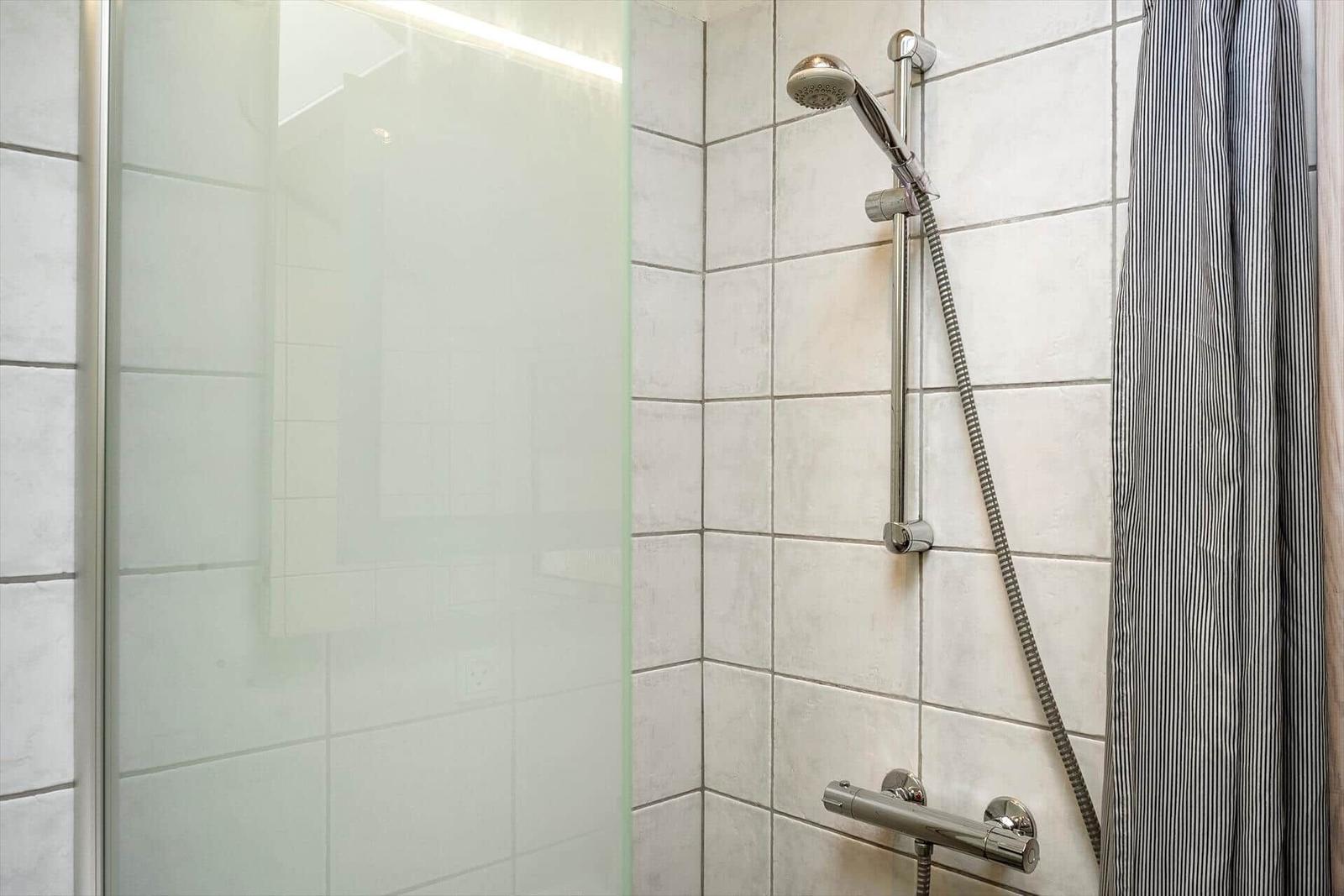 Dusche mit Glaswand und Handbrause an Wand montiert